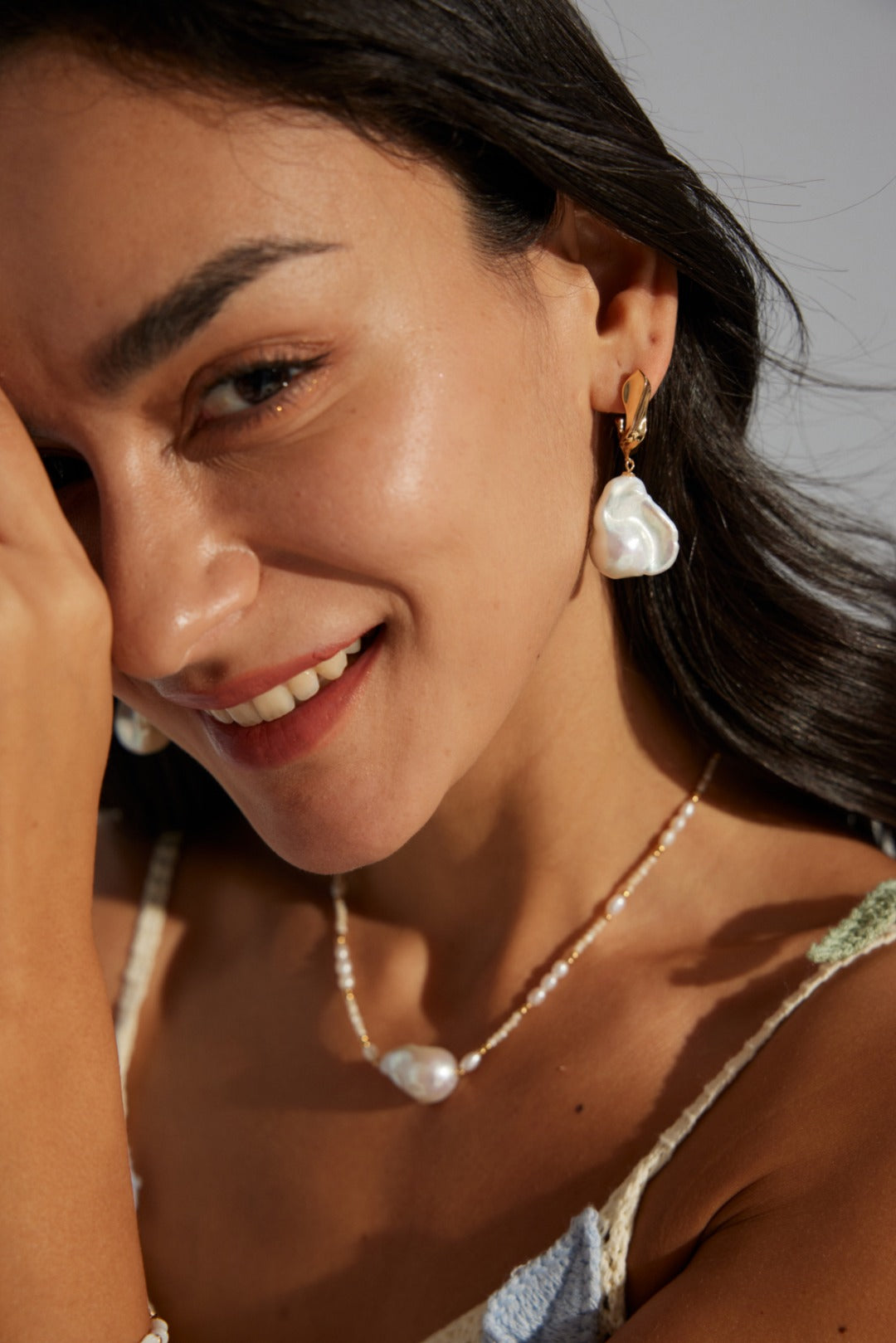 Baroque pearl drop earrings in 18k gold, worn by a model, perfect for elegant vacation looks or destination weddings