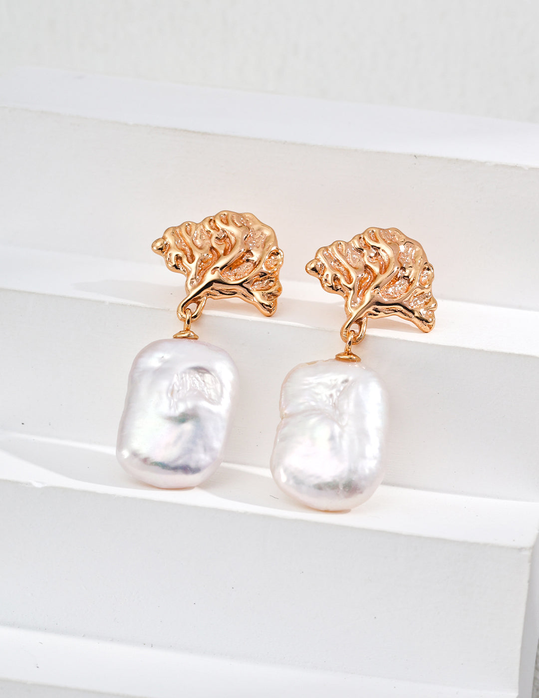 Gold drop earrings featuring intricate leaf designs and dangling baroque pearls, ideal for luxury women’s jewelry collections